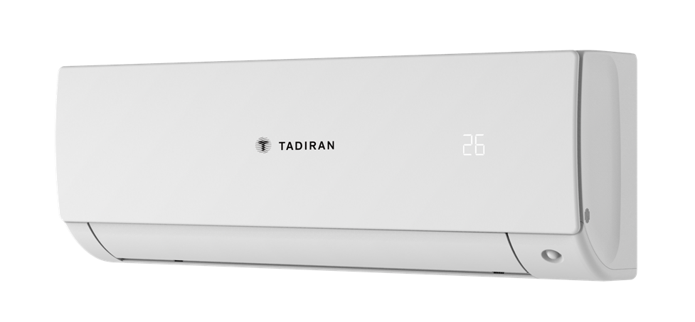 יחידת פנים עילית מעוצבת של מזגן Tadiran Mini VRF בגוון לבן נקי, מותקנת בצורה גלויה על קיר מעוצב בסלון מודרני או במשרד. לצד היחידה מוצג השלט הרחוק / התרמוסטט מדגם PRIME-HQS01. היחידה מציגה קווים נקיים, אסתטיים וזרימת אויר שקטה.